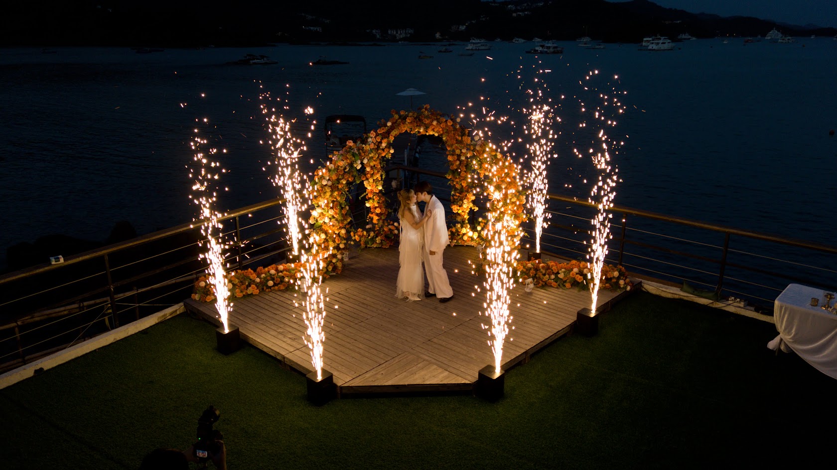 A wedding couple celebrating under sparklers by the water